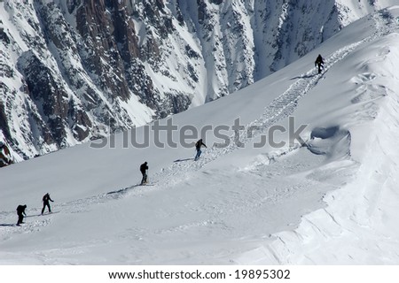 A group of skiers and snow boarders climbing a ridge before skiing off piste on the Mt Blanc