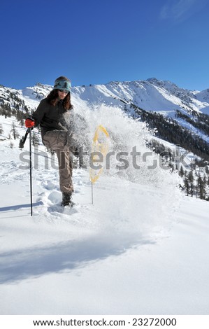 girl with snow shoes sending a cloud of powder snow in the air