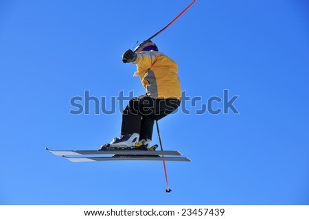Aeroski: skier in a yellow jacket doing a high jump against a deep blue sky