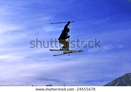 Airoski: silhouette of skier performing a tele-heli (crossed skis) and a full turn during a jump