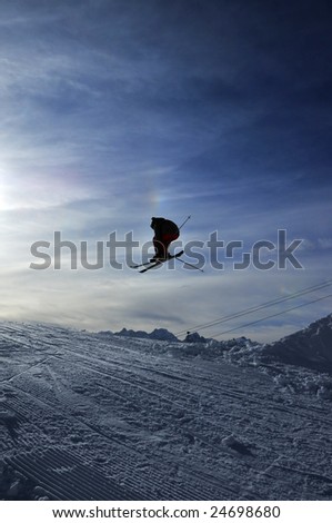 airoski: the silhouette of a skier jumping towards the setting sun