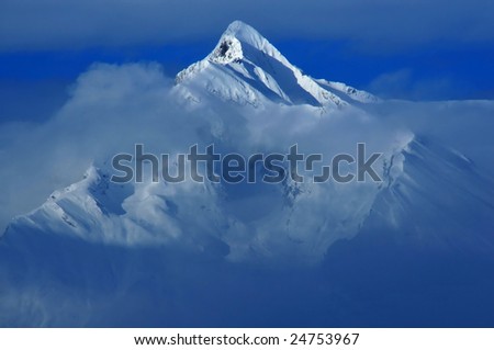 A mountain (Haut du Cry, south face) partially veiled by clouds in the Swiss Alps. This image was made in the winter.