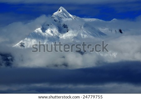 a mountain in the swiss alps with dense layers of cloud at lower altitudes. The mountain is called the Haut du Cry in the Bernese alps., and the image was taken straight after a fresh snow fall