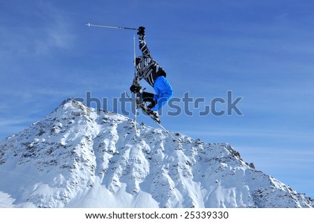 airoski: a skier in bright colorful clothing performing a high jump with his arms akimbo