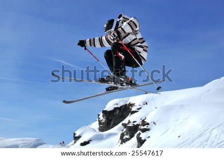 a skier in a crouched position during a jump, preparing to cross his skis