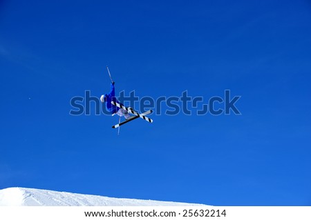 skier in blue and white against a blue sky and on white snow
