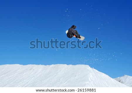 girl snowboarder taking off from a snow ramp followed by a spray of snow