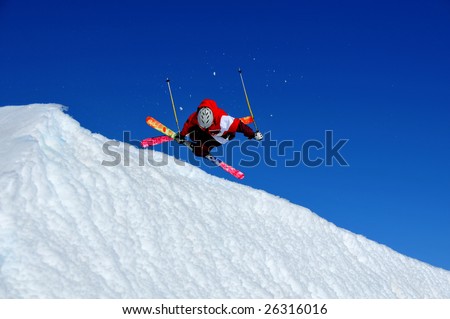 a skier performing a spectacular inverted tele-heli (skis crossed and spinning upside down).