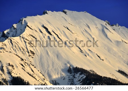 Mountain in the swiss alps (Sex Noir) at sunrise with early rays painting the snow a golden yellow