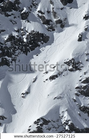 a woman snowboard competitor having made a jump over a rock cliff makes turns down a very steep corridor in the 2009 extreme freeride world championship finals