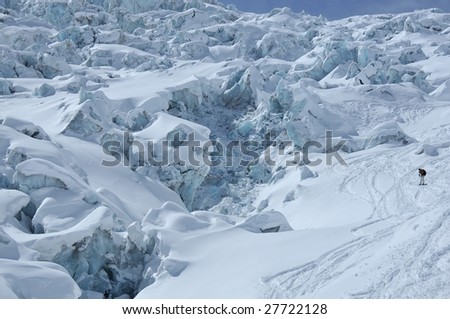 a snowboarder off-piste next to a large ice fall with large blocks of ice, crevasses and seracs.