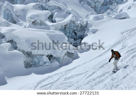 a snowboarder on a glacier next to large blocks of ice and crevasses