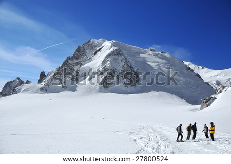 a group of skiers discuss the next move on a high glacier. In the background the mt blanc de Tacul and behind that the Mont maudit. Other groups can be seen in the distance