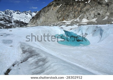 skiers visit an ice lake on a glacier that is growing by the day as the glacier melts. The glacier is melting faster and faster as global warming increases the air temperature