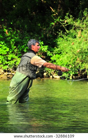 displaying a look of concentration a fly-fisherman casts upstream for a trout.