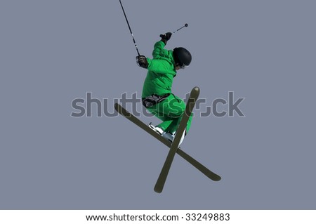 a Tele-hele. A skier executes a perfect crossed skis tele-heli during a high jump isolated on gray background