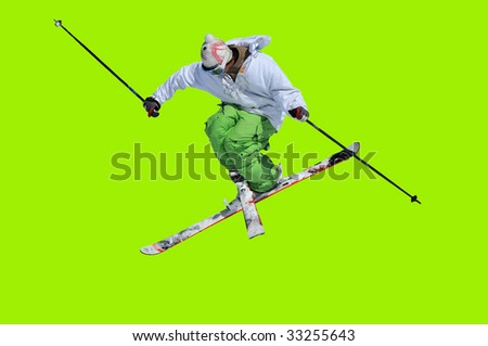 skier in green and white clothes performing a tele-heli with skis crossed at the same time as executing a full spin (in this shot, facing backwards) isolated against a green background