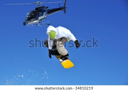 filming with a steady cam mounted on the front of a helicopter of a snowboarder jumping