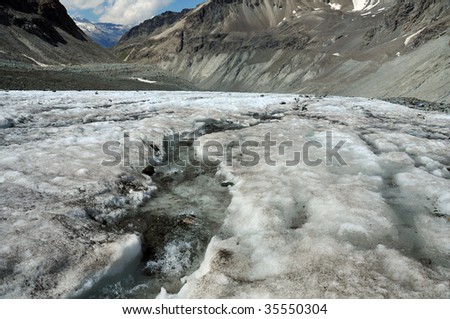 ice melting on a glacier causes a river on its surface. Global warming is causing the worlds glaciers to melt