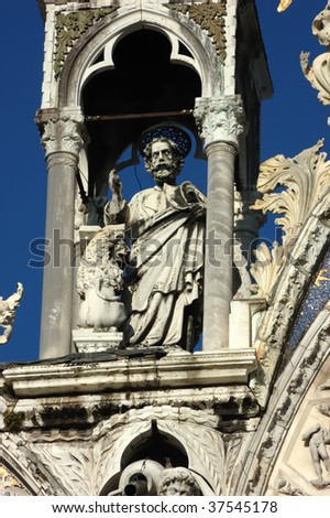 statue of the evangelist Saint Mark on the western facade of Saint Marks Basilica in Venice. Next to him is his symbolic lion supporting his gospel
