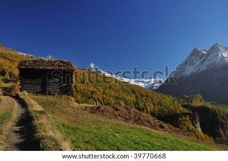 log cabin, forest, and glacier covered mountains in the fall