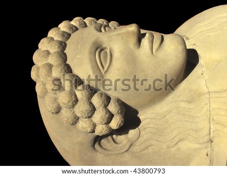 beautiful sculpted face of a woman on an ancient greek marble sarcophagus. Isolated against a black background