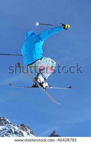 a freeriding ski jumper with crossed skis in blue clothes against a blue sky