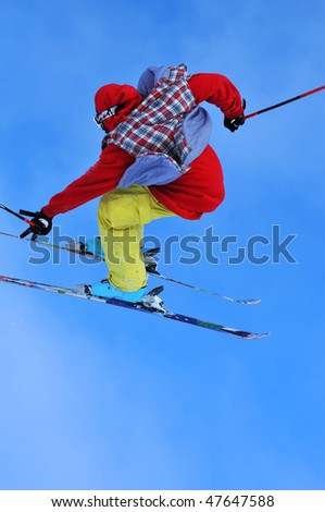 a skier in bright clothes flying through the air