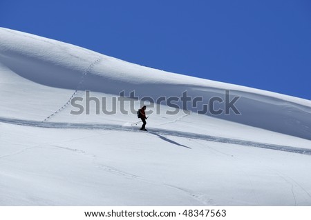 a lone skier skis in fresh powder snow with a clean snow bank behind