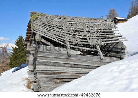 a ruined mountain cabin surrounded by snow