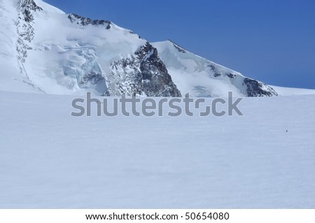line of climbers on a glacial plateau in front of the high swiss peak of Castor in the southern swiss alps