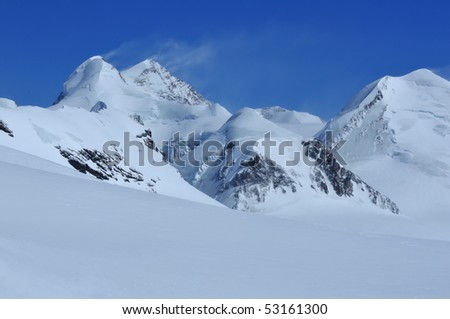 Castor, Pollux and Liskamm in the southern swiss alps, covered by glaciers and snow, with plumes of wind blown snow on the summits