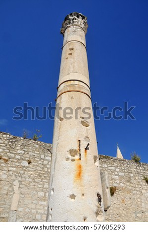 tall roman column with capital and shell holes from attacks in the old forum of Zadar,  Croatia