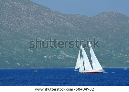 a schooner under full sail leans over mountains in the background