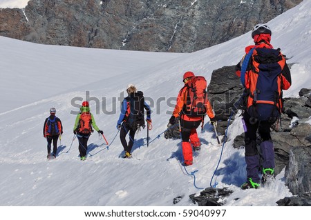 a team of climbers, roped up, descends from the summit