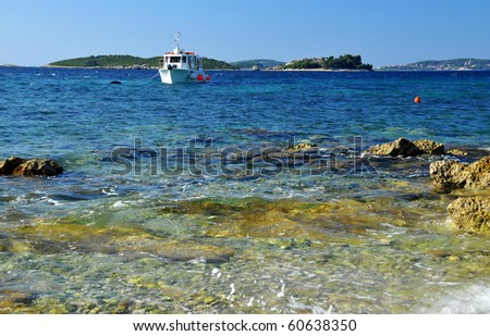 boat riding at anchor in clear clean sea under clear blue skies