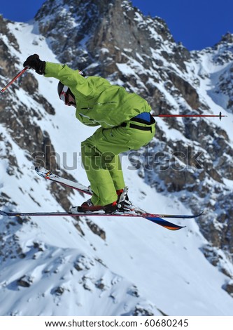 skier in green performing a high jump with crossed skis