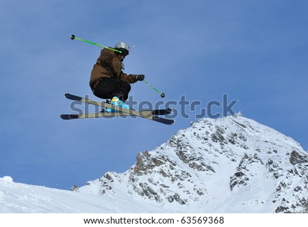 a ski jumper crosses his skis with mountains in the background