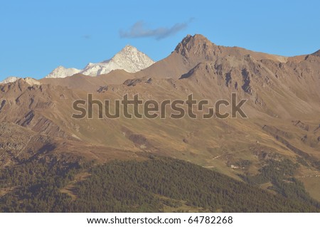 The Zinal Rothorn with its glaciers in the southern swiss alps seen from the west with lesser mountains in the foreground.
