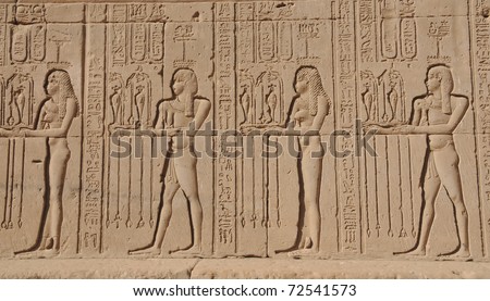 Young and old bare chested women making offerings at the ancient Egyptian fertility and love temple of the goddess Hathor at Dendera, in Egypt