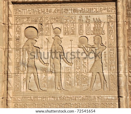 The goddess hathor backed by horus being presented with the solar disk by Osiris wearing the triple Atef crown at the ancient Egyptian fertility and love temple of the goddess Hathor at Dendera, Egypt