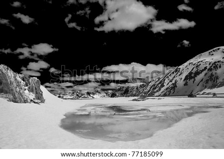 a high mountain pass in the spring with frozen lake starting to melt, and the road over the top just opened.