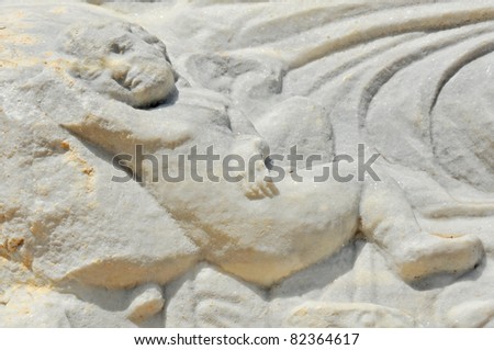 ancient roman carving of a dead child resting in peace, sculpted onto the lid of his sarcophagus in white marble