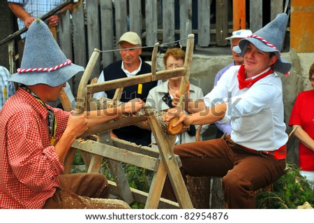 EVOLENE, SWITZERLAND - AUGUST 15: Traditional wood cutting at the International Festival of Folklore and Dance from the mountains (CIME) : August 15, 2011 in Evolene Switzerland
