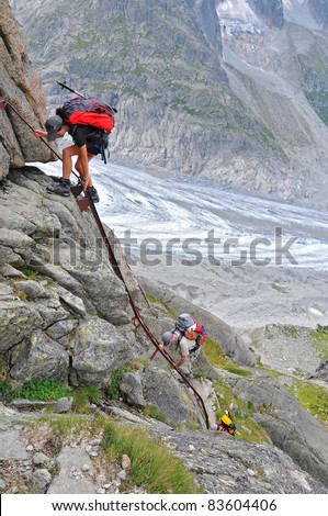 girl climber on a rock face ladder, climbing down with glacier in the background and no security