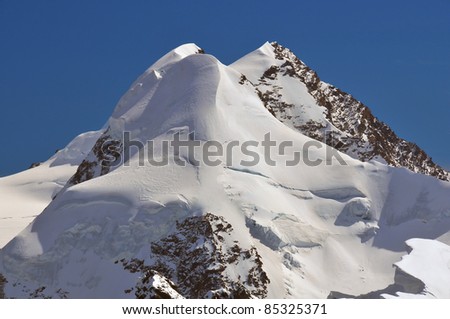 the ice covered twin peaks of Liskamm in the southern swiss alps above Zermatt viewed from the summit of the Breithorn