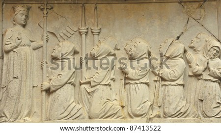 Saint Fosca, the virgin saint of Ravenna with monks kneeling in devotional prayer. 11th century sculptural scene