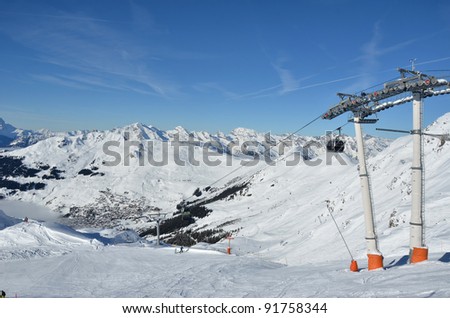 Skiing in the famous ski resort of Verbier in the Swiss Alps. In the background the bernese alps. In the foreground empty slopes with just a few skiers on fresh snow.