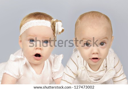 Twin baby brother and sister in white clothes