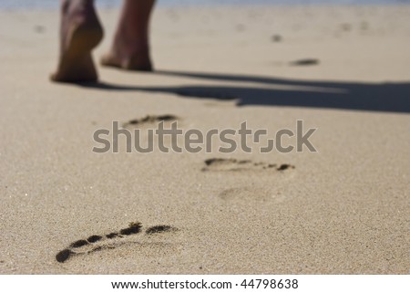 The feet of a lonely person walking on the beach leaving behind only footprints